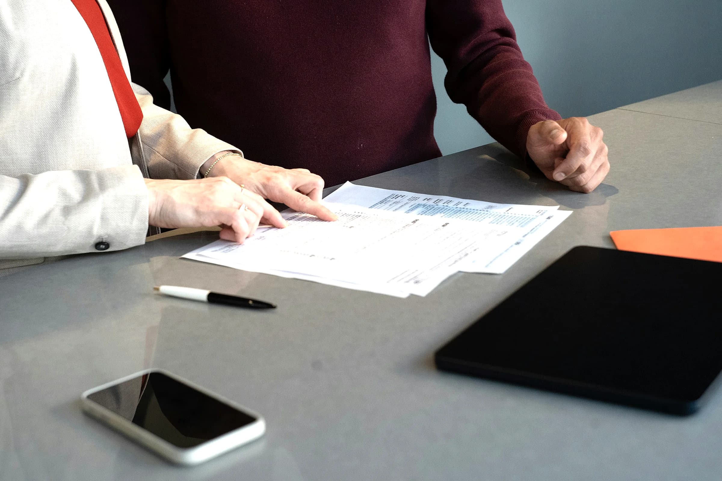 Two people review printed documents together at a table
